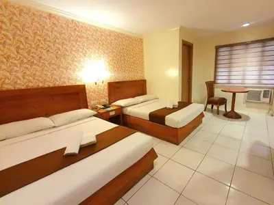 a hotel room with two beds and a table at Rosas Garden Hotel in Manila