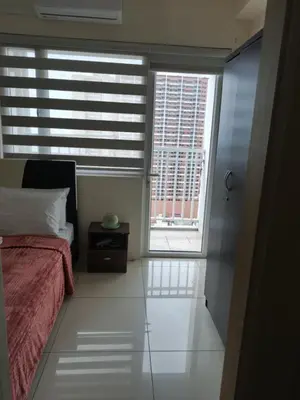 a bedroom with a bed and two windows at De Luxe, Standard and Studio Suites -The Breeze Residences-close to Airport,Mall of Asia, US Embassy in Manila