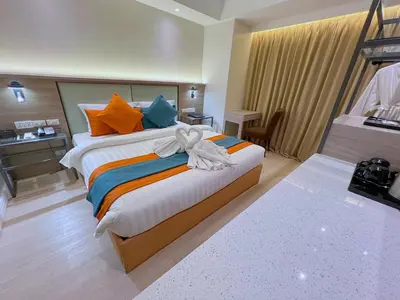 a bedroom with a large bed with orange and blue pillows at City Garden Hotel Makati in Manila