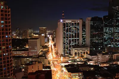 a city lit up at night with buildings at City Garden Hotel Makati in Manila