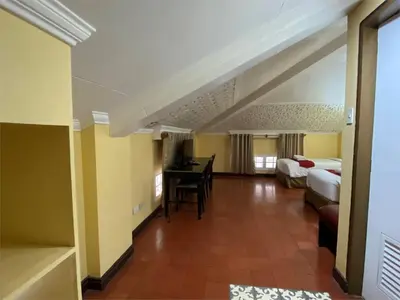 a hotel room with two beds and a desk at White Knight Hotel Intramuros in Manila