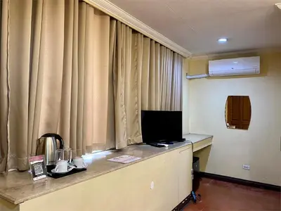 a room with curtains and a desk with a television at White Knight Hotel Intramuros in Manila