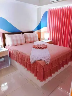 a bedroom with a large bed with red curtains at Holiday Escape Philippines in Manila