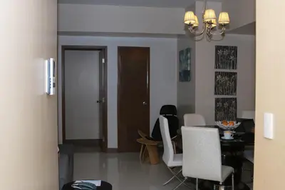 a dining room with a table and white chairs at De Luxe 7QRS in Manila