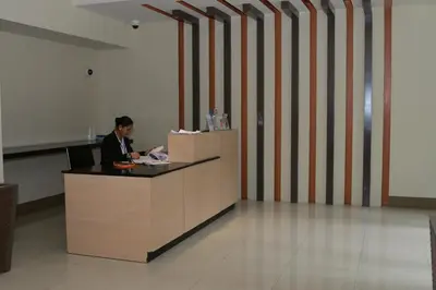 a man sitting at a reception desk in a lobby at De Luxe 7QRS in Manila