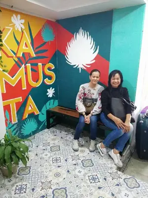 two people sitting on a bench in front of a wall at Frank Lloyd Apartelle in Manila