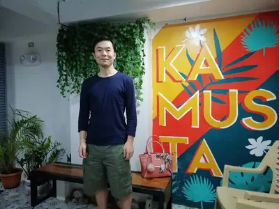 a man is standing in front of a sign at Frank Lloyd Apartelle in Manila