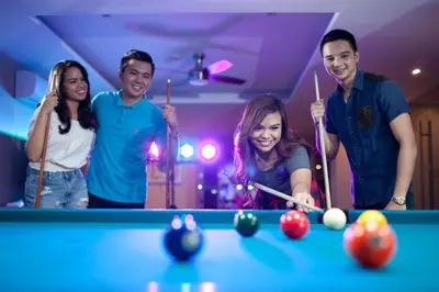 a group of people standing around a pool table at Mount Sea Resort in Rosario
