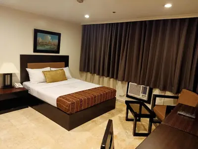 a bedroom with a bed and a desk and a chair at Paragon Tower Hotel in Manila
