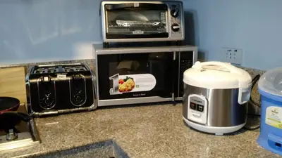 a kitchen counter with a microwave and a toaster oven at Burgundy McKinley Place in Manila