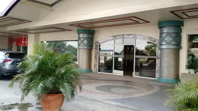 a building with a palm tree in front of it at Burgundy McKinley Place in Manila