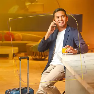 a man sitting at a table talking on a cell phone at Savoy Hotel Manila near Airport NAIA Terminal 3 MNL in Manila