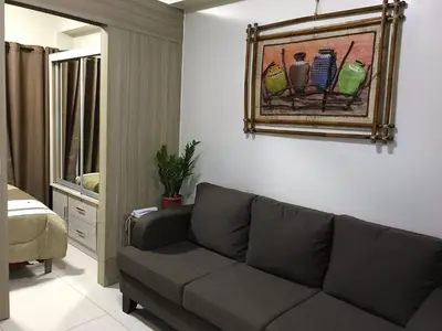 a living room with a couch and a painting on the wall at Manila Bay Breeze Residences with Pool View in Manila