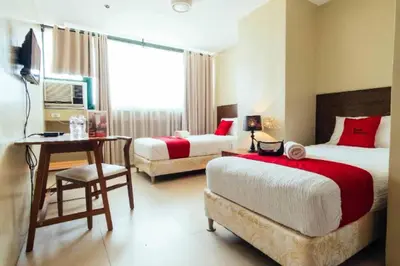a bedroom with two beds and a table and a desk at RedDoorz near Osmena Highway 1 in Manila