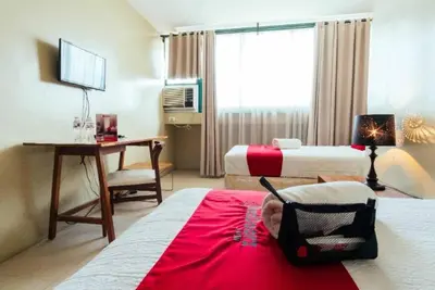 a hotel room with two beds and a desk at RedDoorz near Osmena Highway 1 in Manila