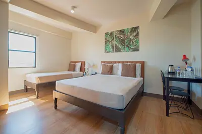 a bedroom with two beds and a desk in it at Achievers Airport Hotel in Manila