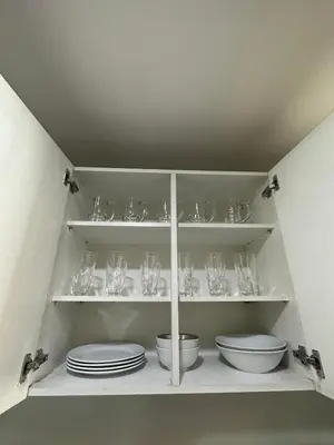 a white shelf with plates and glasses on it at Suites de Marina Manila with Netflix in Manila