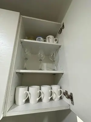 a cupboard filled with white mugs and wine glasses at Suites de Marina Manila with Netflix in Manila