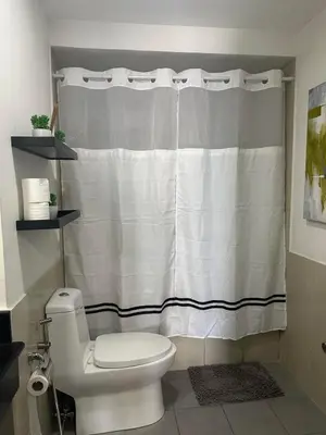 a bathroom with a toilet and a shower curtain at Suites de Marina Manila with Netflix in Manila