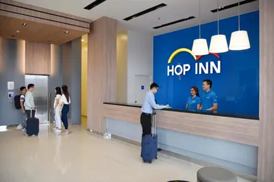 a group of people standing around a hipper inn counter at Hop Inn Hotel Aseana City Manila in Manila