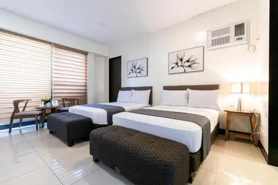 a hotel room with two beds and a table at Artemis Place Makati Hotel in Manila