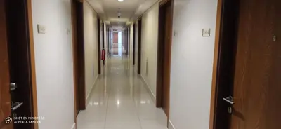 a long hallway with white tile floors and doors at Shell Residences in Manila