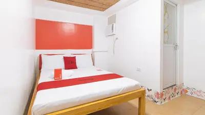 a small bedroom with a bed with a red headboard at RedDoorz at DBuilders Rooms Ph1 Taguig in Manila