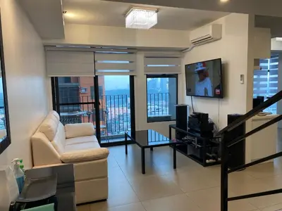 a living room with a white couch and a tv at Penthouse suite at Porto Vita Towers in Cubao Quezon City in Manila