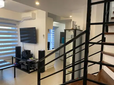 a living room with a staircase with a flat screen tv at Penthouse suite at Porto Vita Towers in Cubao Quezon City in Manila