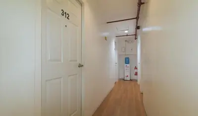 a hallway with a white door and a wooden floor at RedDoorz Plus at Boni Avenue Mandaluyong in Manila