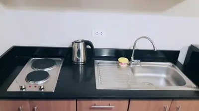 a kitchen counter with a sink and a stove at Palm Tree Villas 1 in Manila