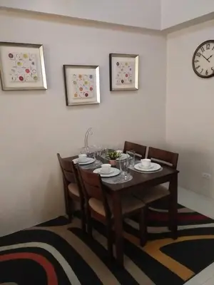 a dining room table with chairs and a clock on the wall at Palm Tree Villas 1 in Manila
