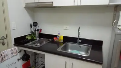 a kitchen with a sink and a black counter top at Jazz Residences Condo in Manila