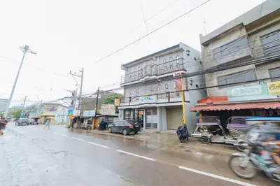 a city street in the rain with cars and buildings at RedDoorz at San Antonio Binan Laguna in Biñan