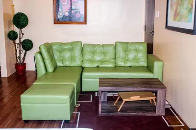 a green couch in a living room with a coffee table at Titan 22P Condo at WH Taft Residences Manila in Manila