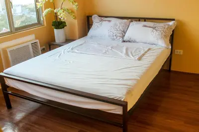a bed with white sheets and pillows in a room at Titan 22P Condo at WH Taft Residences Manila in Manila