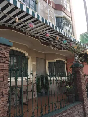 a house with a wrought iron fence and christmas lights at 1 River Central Hostel in Manila