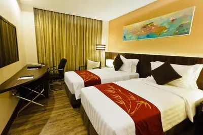 a hotel room with two beds and a desk at Ramada by Wyndham Manila Central in Manila