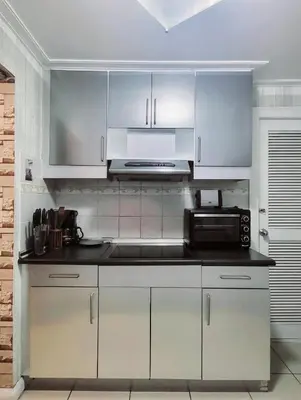 a kitchen with white cabinets and a microwave at 67 sqm. Condo Unit in Robinson Place Residences in Manila