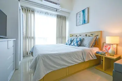a bedroom with a large bed and a television at Amora Suites at the Beacon Makati in Manila
