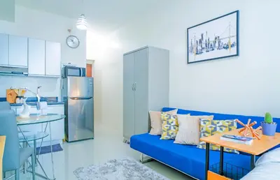 a living room with a blue couch and a kitchen at Amora Suites at the Beacon Makati in Manila
