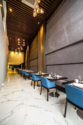 a dining room with tables and blue chairs at Ramada Encore by Wyndham Makati in Manila
