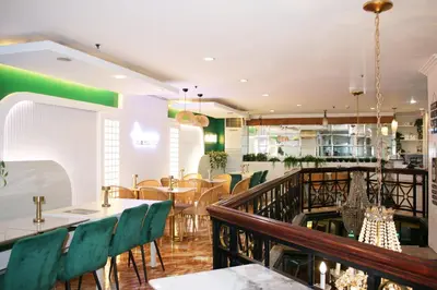 a restaurant with green chairs and tables and a bar at Lourdes Family Suites Makati powered by Cocotel in Manila