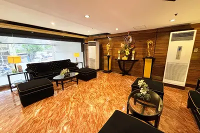 a living room with black furniture and a wooden floor at Lourdes Family Suites Makati powered by Cocotel in Manila