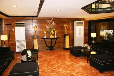 a living room with couches and a table with flowers at Lourdes Family Suites Makati powered by Cocotel in Manila