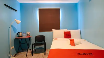 a blue room with a bed and a table at RedDoorz at Hotel Rosemarie in Manila