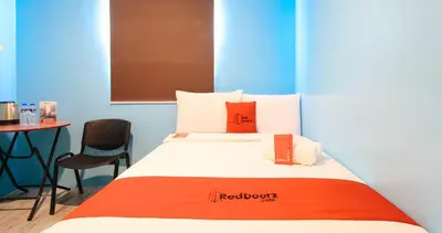 a bed with orange and white pillows and a table at RedDoorz at Hotel Rosemarie in Manila