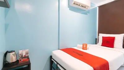 a small room with a bed with a red blanket at RedDoorz at Hotel Rosemarie in Manila