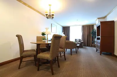 a living room with a dining room table and chairs at Tiara Oriental Hotel Makati powered by Cocotel in Manila
