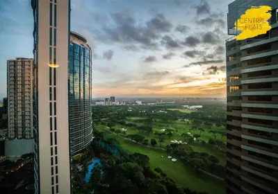 a view of a golf course between two tall buildings at Prime Avant BGC Location Apartments by PH Staycation in Manila